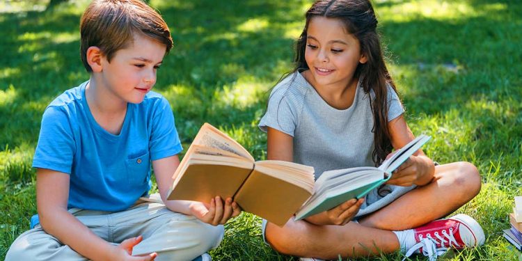 Dos niños con libros para celebrar el Día Internacional de la felicidad