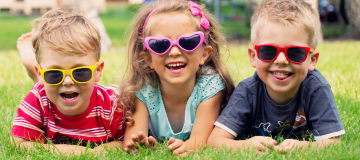 tres niños con divertidas gafas de sol y riendo para feliz verano