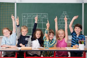 Cultura emprendedora en educación con niños entusiasmados en clase levantando la mano par acontestar