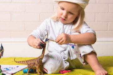 niño pintando dinosaurio para ejemplificar manualidades infantiles de dinosaurios