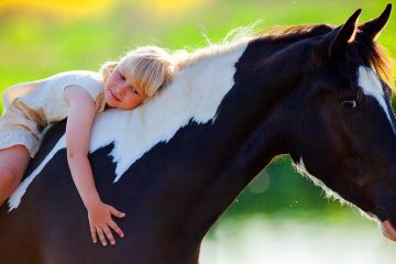 Niña abrazada a un caballo para ilustrar la fascinación infantil por los animales
