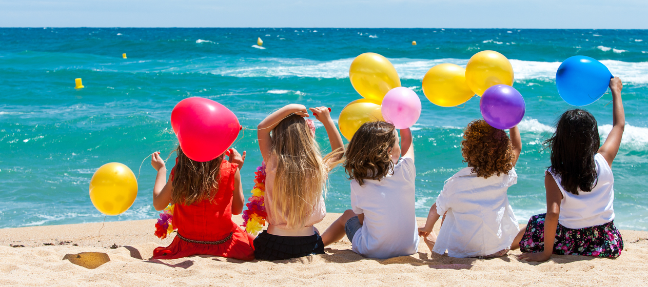 Niños en la playa con globos para felices vacaciones