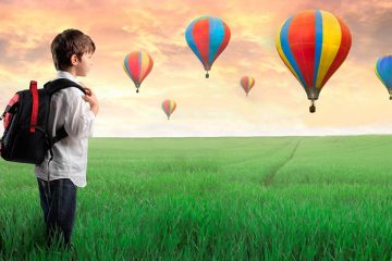 Nen amb una motxilla mirant globus aerostàtics per il·lustrar els llibres per viatjar
