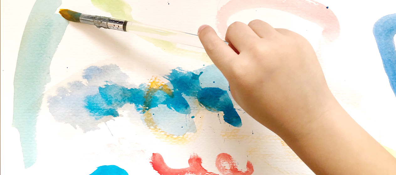 Mano de niño dibujando con pintura de colores
