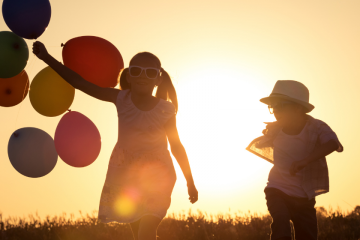 nena amb globus i nen a contrallum en posta de sol per articles per gaudir amb calma