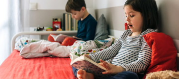 dos niños leyendo en voz alta en la cama para beneficios de leer en voz alta