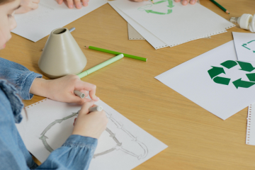 Niños en una mesa dibujando reciclaje