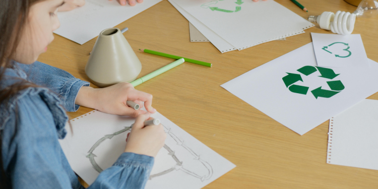Niños en una mesa dibujando reciclaje