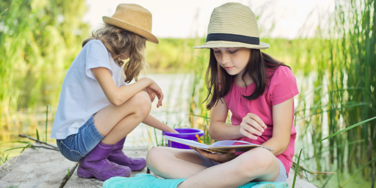 Niñas leyendo al aire libre como parte de la propuesta de verano con ZigZag y ¡Splash!